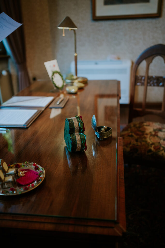 Ein hölzerner Schreibtisch mit Papieren, einer Lampe und kleinen dekorativen Kisten in einem gemütlichen Raum im Vintage-Stil - perfekt für die Planung Ihres Standesamtes oder Ihrer Freien Trauung.