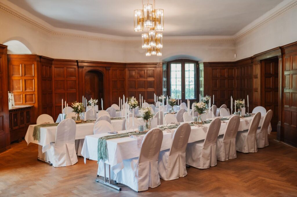 Elegantes Esszimmer mit Holzvertäfelung, weiß gedeckten Tischen und Stühlen für eine formelle Veranstaltung - perfekt für alle, die einen exklusiven Dekoverleih oder Dekorationsservice in Berlin suchen.